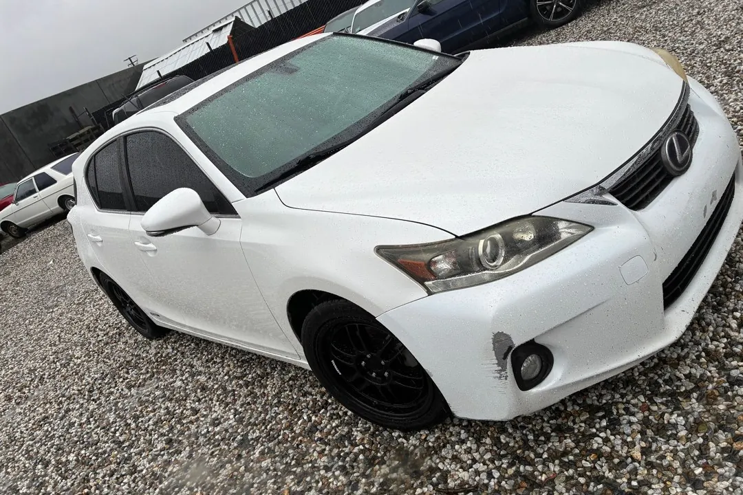 A white Lexus CT hybrid on a gravel lot.